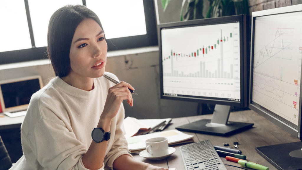 Компьютерная клавиатура на фоне монитора с графиком, человек смотрит на доску.