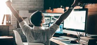 Человек счастливо улыбается перед монитором с компьютерной аппаратурой.