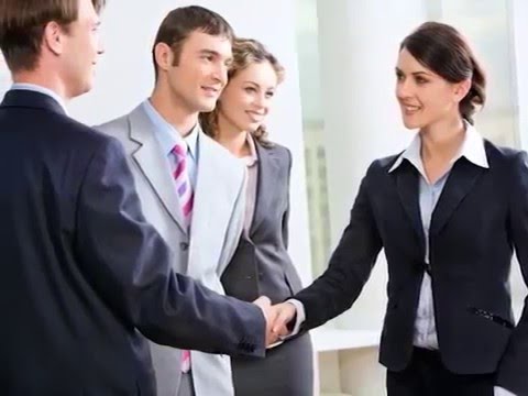 Исполнитель в мужском костюме с улыбкой, носит пиджак и пальто.