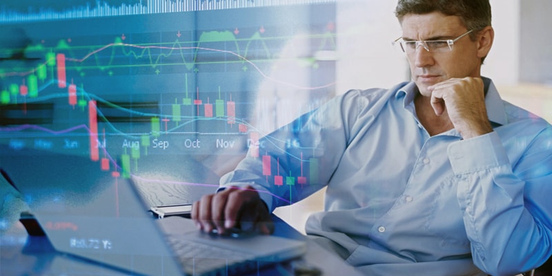 Взрослый мужчина стоит, одет в костюм, серьезное выражение лица.