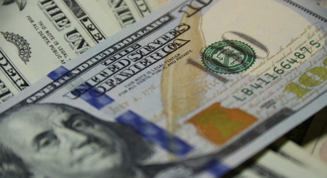 Человек с долларами в руках, крупным планом лица и головы.