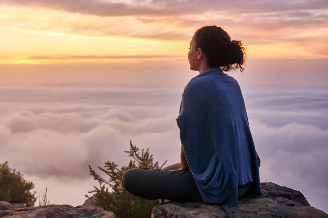 Человек сидит на природе под открытым небом, занимается йогой. Фотография фитнеса и спорта.