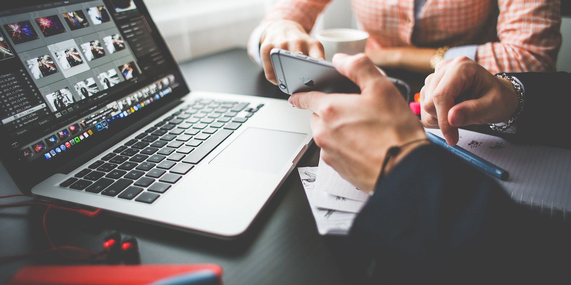 Клавиатура, ноутбук, монитор, смартфон, человек пишет текст ручкой на компьютере.