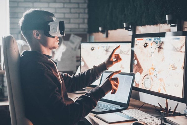 Клавиатура, монитор, VR-очки, ноутбук и игры - человек использует электронику.