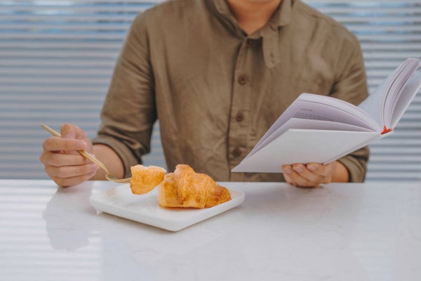 Мужчина-взрослый с книгой красиво сервирует тарелку с едой и картофельными дольками.