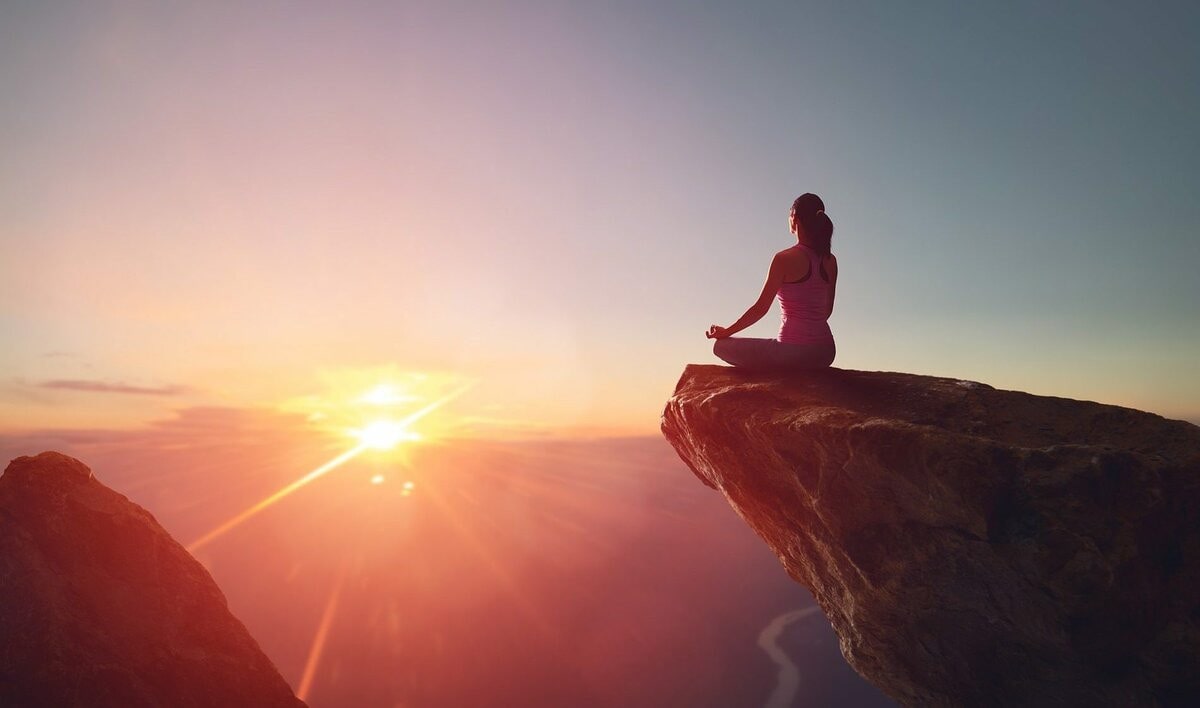 Женщина занимается йогой на рассвете на открытом воздухе под небом.