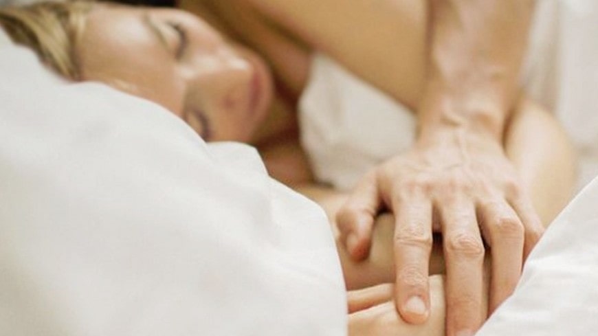 Человек в оранжевой куртке стоит на вершине горы, глядя вдаль.