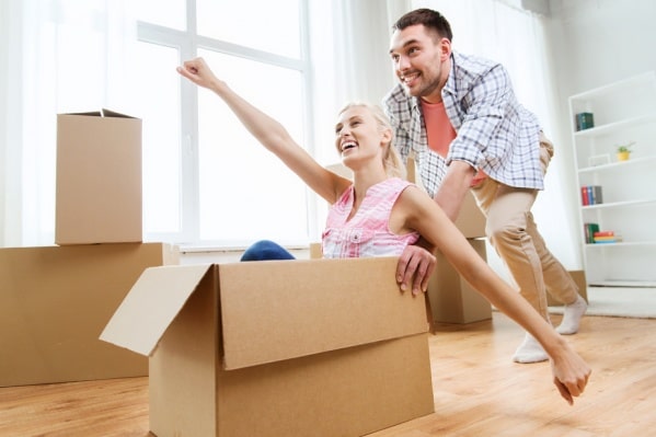 Человек счастливо улыбается, держа коробку на голове.