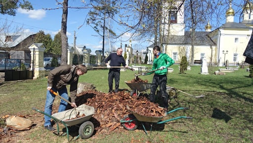 Взрослый мужчина с перчаткой и кроссовками рядом с машиной на заднем плане.