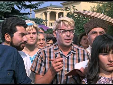 Мужчина с галстуком, в очках, держит рукой пальцем у виска.