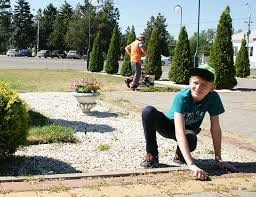 Фото мужчины-садовника подростка, работающего в саду, посреди парка на открытом воздухе.