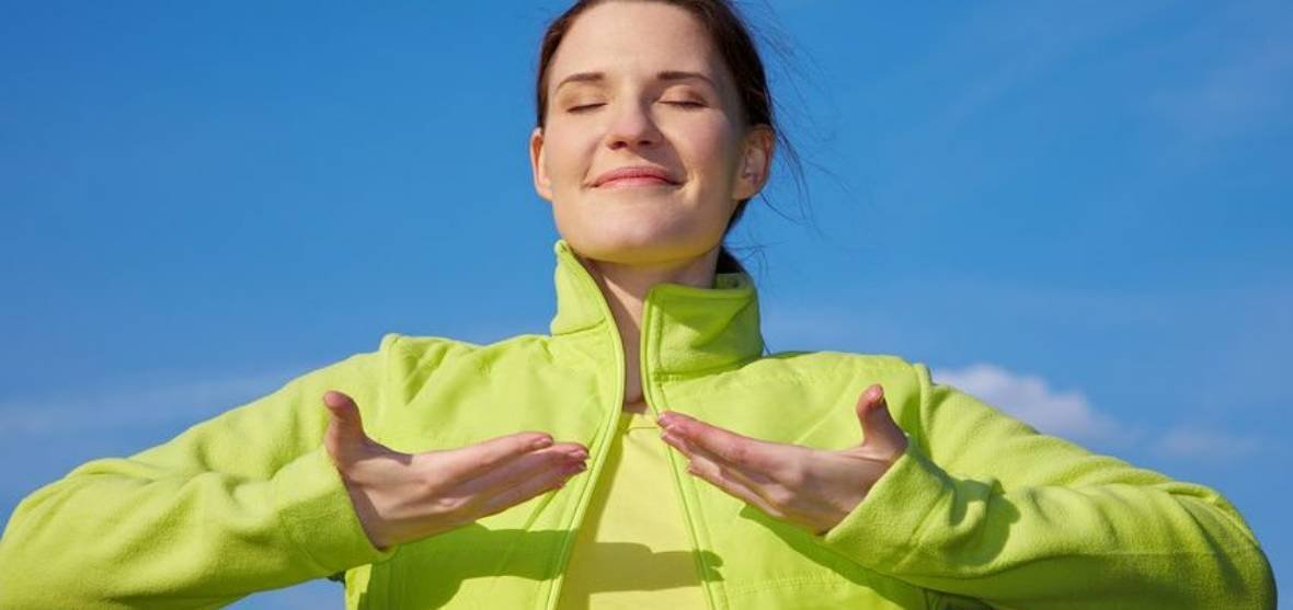 Женщина в куртке занимается йогой, лицо видно, взрослая.