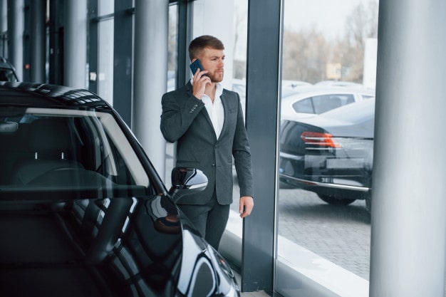 Мужчина-взрослый в костюме и пиджаке у автомобиля, вид с лица.