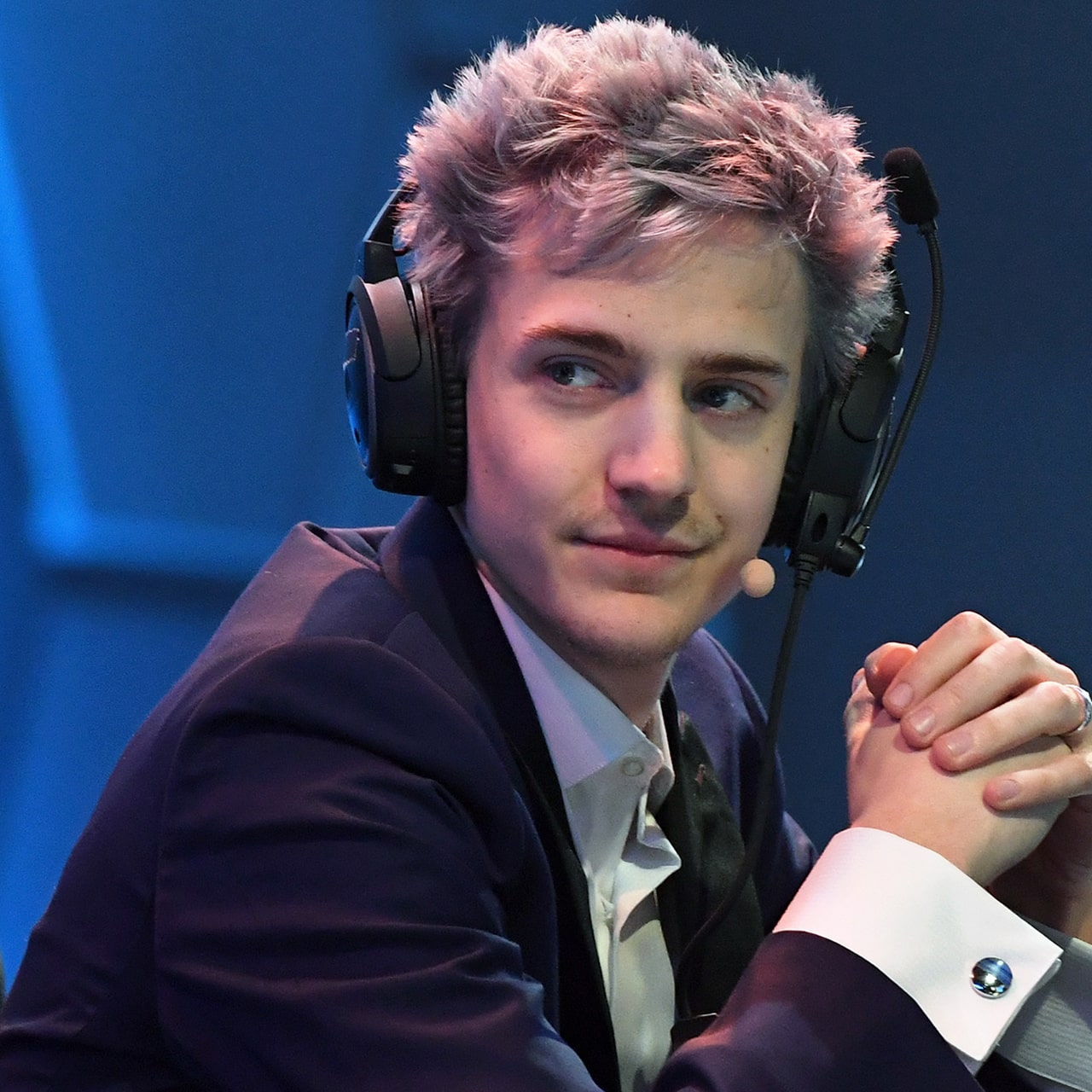 Фото человеческой руки с одним микрофоном рядом, слушалками и электронным устройством.