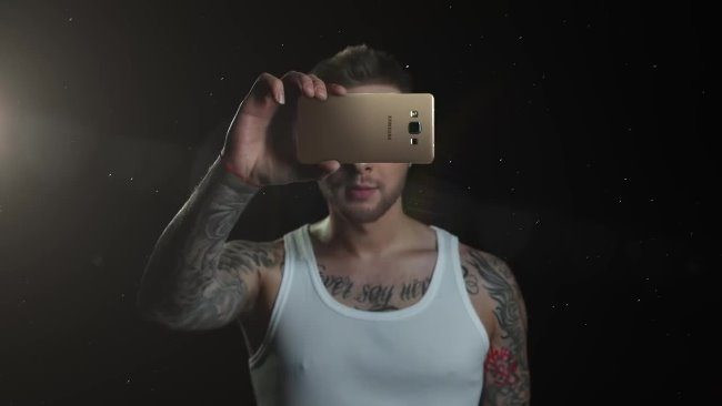 Фото человека с татуировкой на лице, селфи с мобильным телефоном.