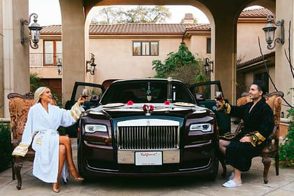 Женщина-водитель стоит около чёрной лимузины с машины с номером.