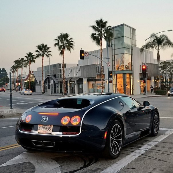 Машина с легкосплавным колесом и светофором, автомобиль и человек на дороге.