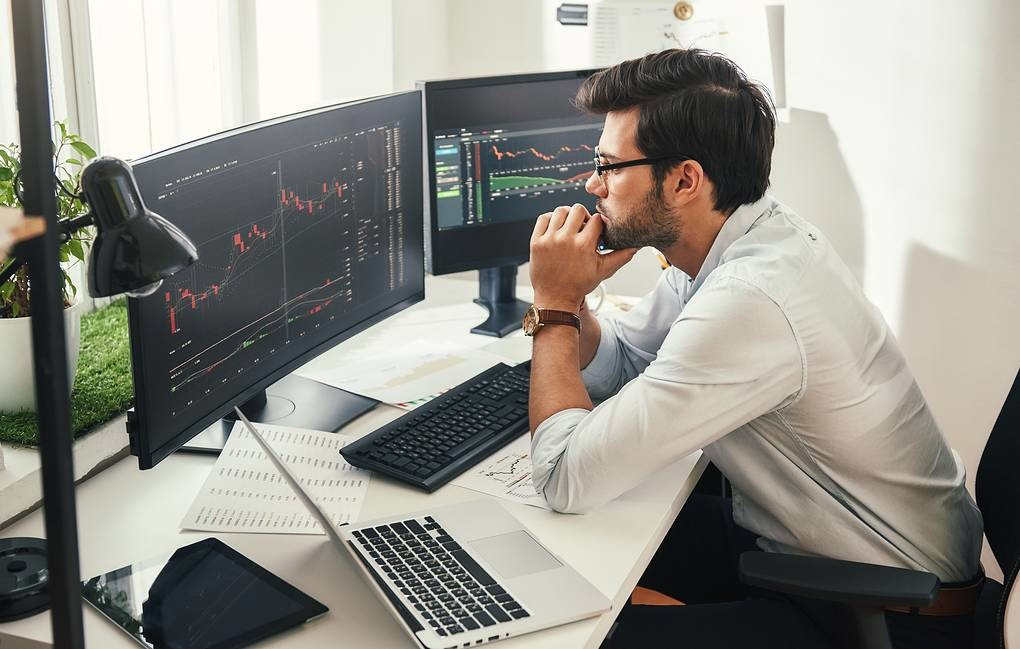 Картинка взрослого мужчины с компьютерной клавиатурой и монитором на рабочем столе.