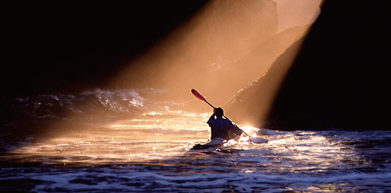 Весла для каяка: взрослый мужчина гребет в лодке с вёслами.