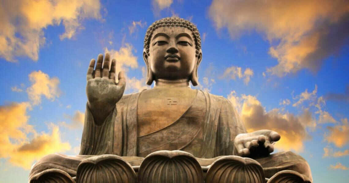 Мужчина-монах молится перед статуей Будды, выражая искусство и духовность.