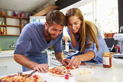 Взрослый мужчина с ножом, держит пиццу перед лицом.