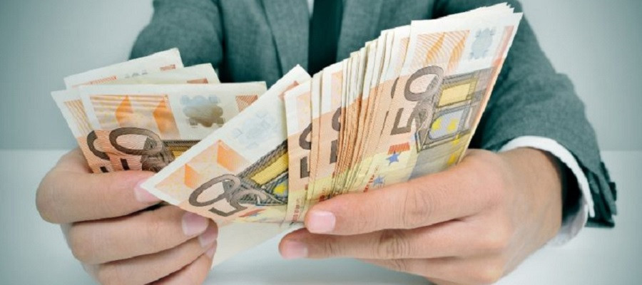 Деньги - купюры разных номиналов, валяются на деревяном столе в стопке.