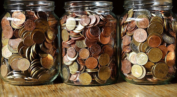 Стеклянный баночка с монетами для накоплений, символизирующая деньги.