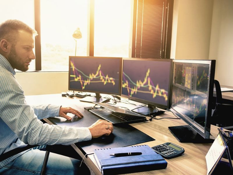 Взрослый мужчина смотрит на монитор экрана, сидя за столом в офисе.