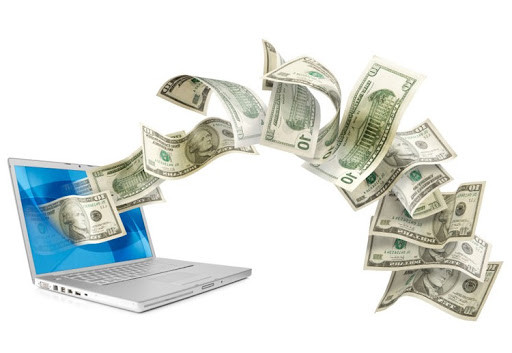 Новый ноутбук с клавиатурой и деньгами на фоне электроники и компьютерных компонентов.