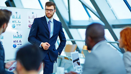 Взрослый мужчина в пиджаке и женщина в пальто у доски.