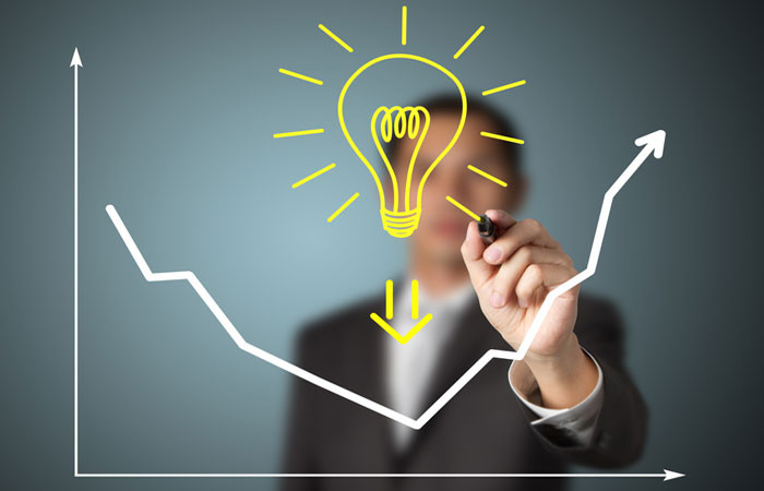 Человек-рука держит отвертку около устройства с лампочкой на фоне света.