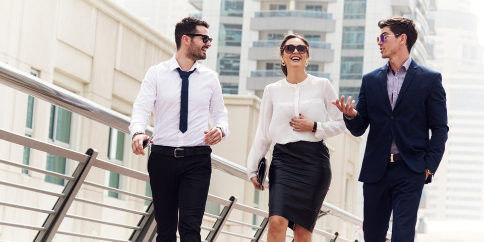 Взрослая женщина в пальто и юбке с поясом, мужчина в галстуке.