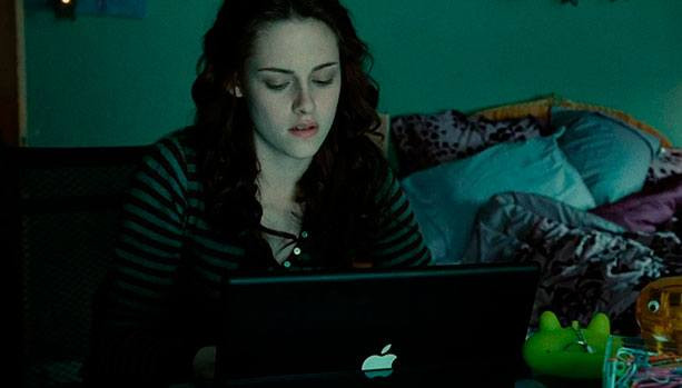 Компьютер и ноутбук на фоне мебели для спальни, диван и женщина на кровати.