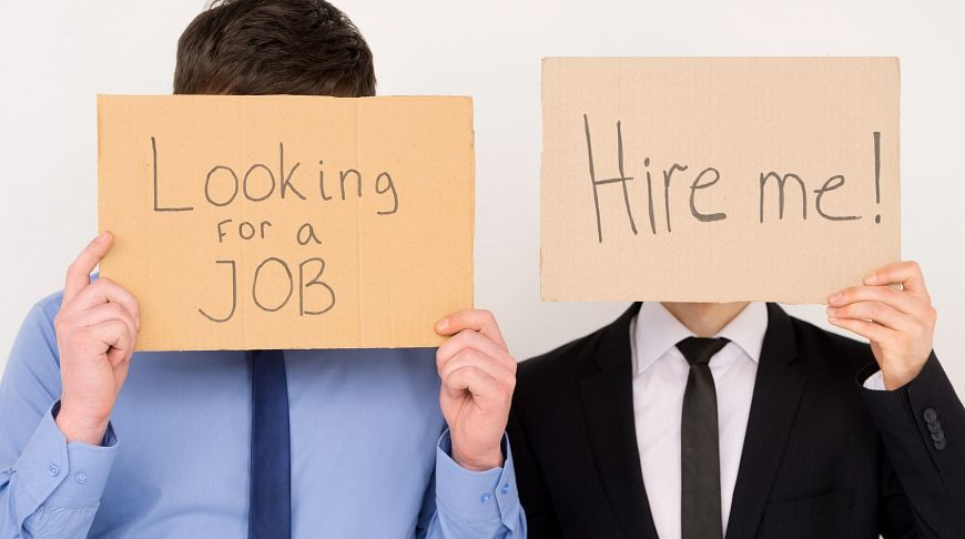 Мужчина в деловом костюме с галстуком, держит в руке визитную карточку.