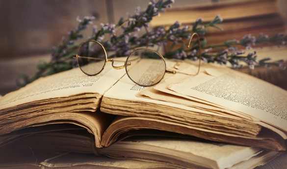 Человек в очках читает книгу с аксессуарами на фоне публикаций.