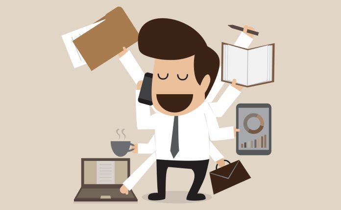 Человек с головой в коробке, на фоне компьютера и электроники.