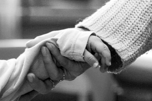 Человек держит за руку младенца: кисть, пальцы, рука, тело - описание изображения.