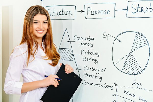 Женщина-взрослая с ручкой на фоне белой доски, лицо и голова в кадре.