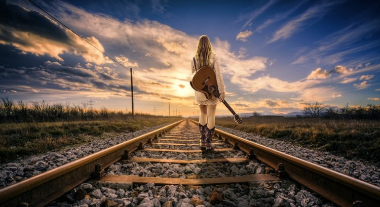 Фотография гитариста с гитарой, который гуляет среди облаков с музыкальным инструментом.