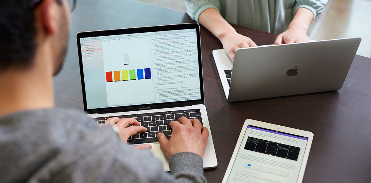 Мужчина взрослый сидит за столом с ноутбуком и планшетом, фокус на лице.