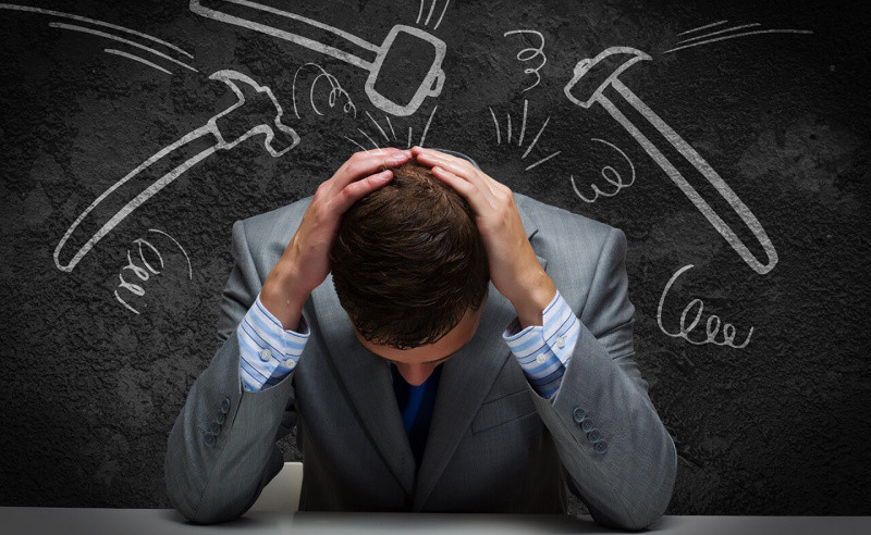 Взрослый мужчина в классическом костюме, стоит перед доской, сосредоточенно глядя.