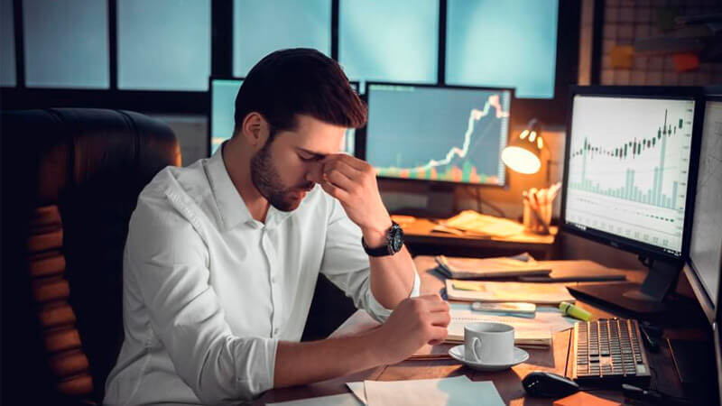 Человек смотрит на компьютерный монитор, держит чашку кофе в руке.