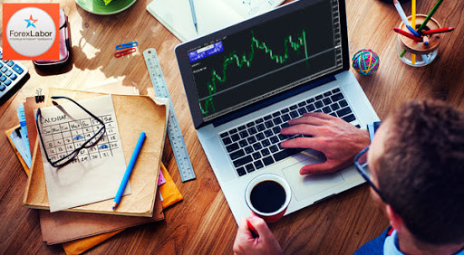 Электроника, ноутбук на столе, взрослый мужчина с ручкой, монитор в фоне.