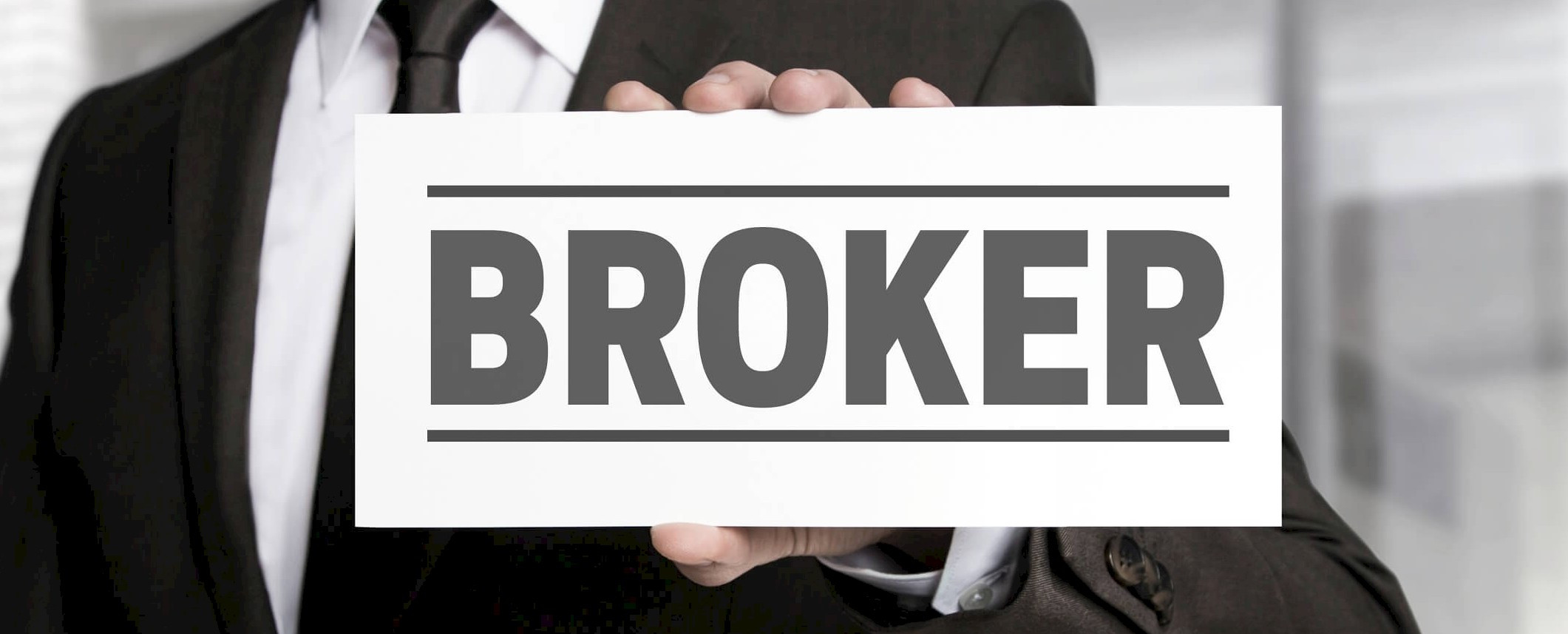 Мужчина в формальной одежде: костюм, пиджак, рубашка, галстук, брелок с текстом.