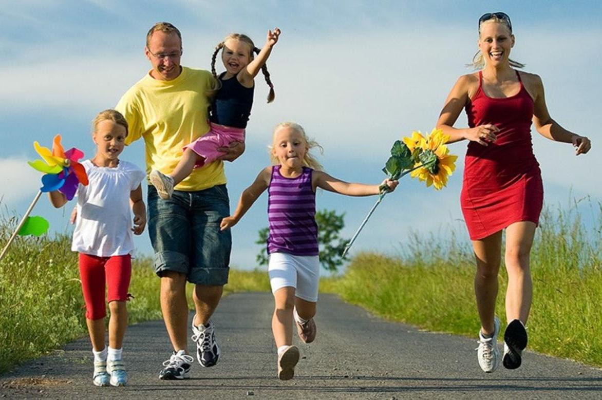 Ребенок-девочка в шортах и туфлях идет, взрослая женщина в фоне.