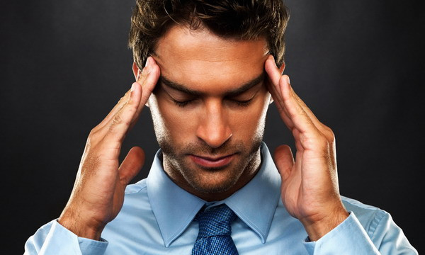 Мужчина с болью на лице в деловом костюме с галстуком.