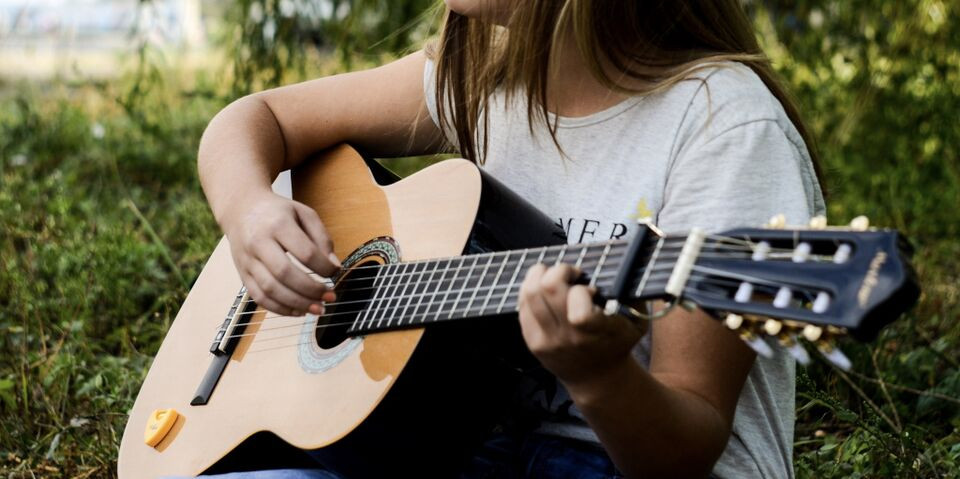 Гитарист играет на гитаре на свежем воздухе, исполняя музыку для зрителей.