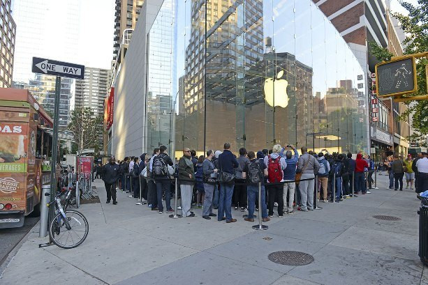 Городская улица с людьми, велосипедом и автобусной остановкой возле светофора.