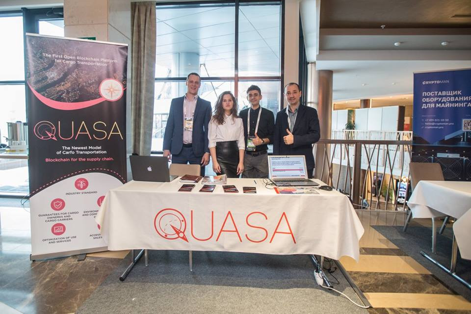 "Professional adult male in a suit standing at table in crowded room."