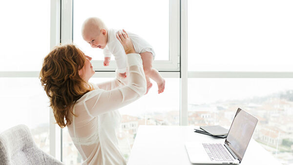 Голова младенца смотрит на ноутбук с монитором, клавиатурой и людьми.